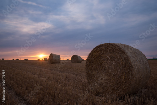 Sun shining between hay bales at sunset