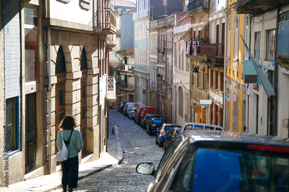 A narrow street in Europe, a lot of parked cars, mountain Porto, high rises and low descents