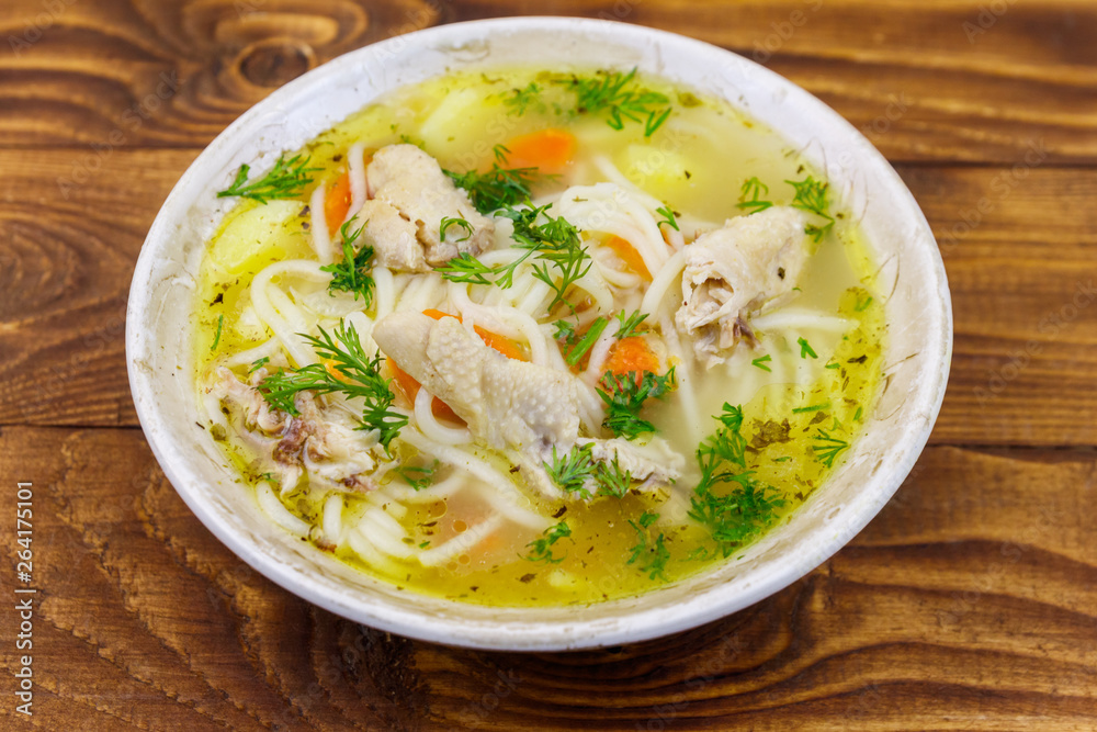 Chicken soup with noodles and vegetables on wooden table