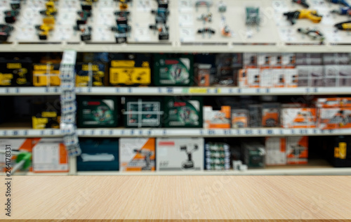 Shop for selling electric tools. Drills, screwdrivers, electric saws, grinder. Defocused, blurred image. In the foreground is the top of a wooden table, counter.
