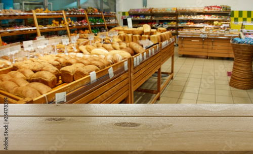 Department of baking in the supermarket. In the foreground is the top of a wooden table, counter.
