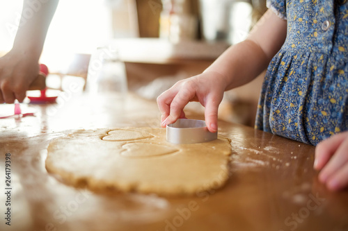 child in the kitchen makes homemade cookies. kid cook at home. girl cuts hearts with a cutter