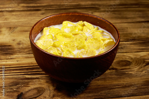 Cornflakes with milk in a bowl on wooden table