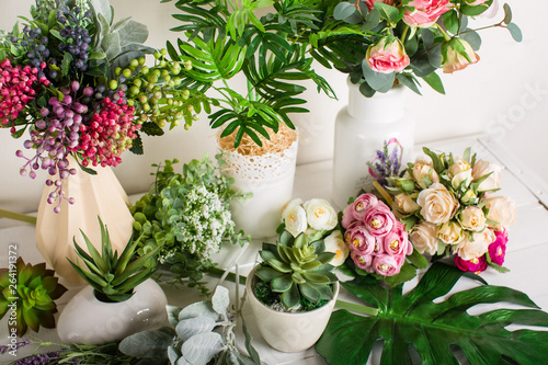 Various artificial flowers, bouquets in vases, succulents