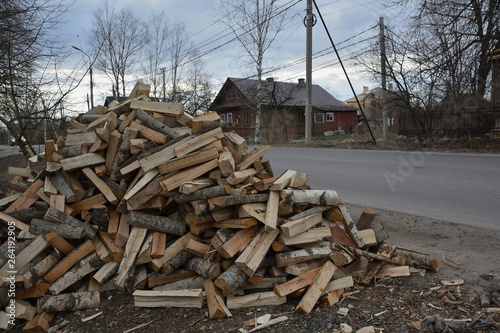 Hill of firewood against the background of the road and the house