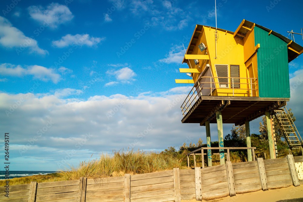 Brightly coloured lifeguard observation tower on sandy beach of Tasman Sea shoreline in Australia.