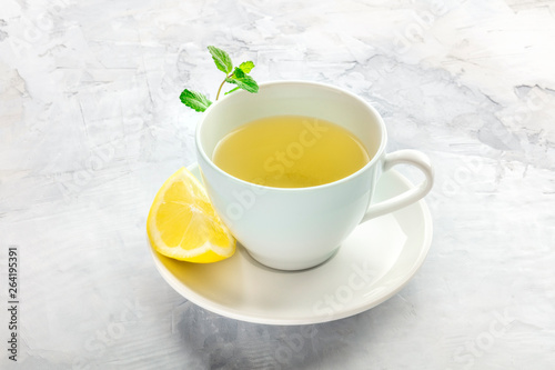 A photo of a cup of tea with a slice of lemon and mint leaves, with a place for text