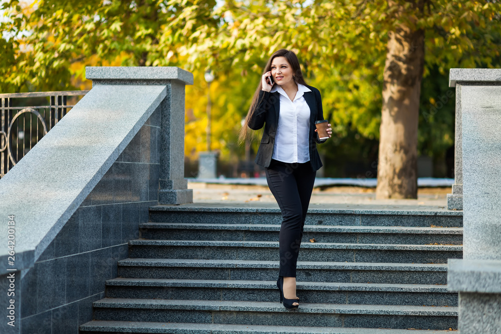 Businesswoman talking on phone while walking outdoor