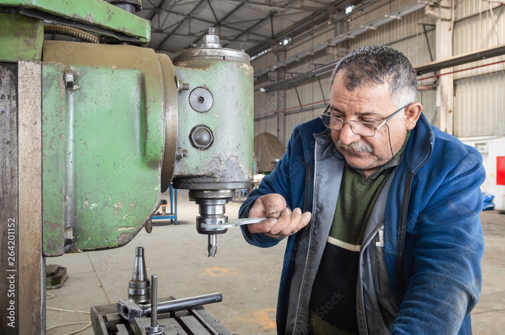 Blue-collar worker using milling machine in workshop Blue-collar worker using milling machine in workshop