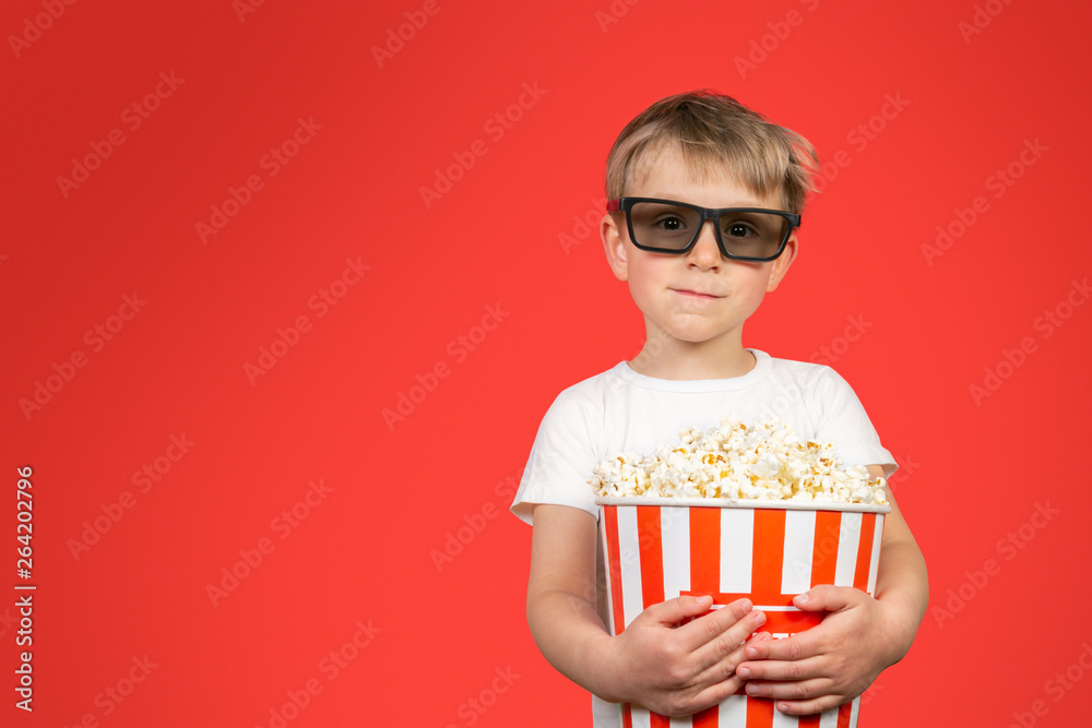 Movie concept - boy holding huge popcorn basket, bright red background