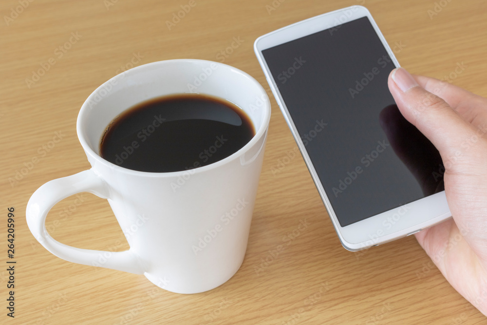 スマートフォンを操作しながらコーヒーを飲む スマートフォンを操作しながらコーヒーを飲む