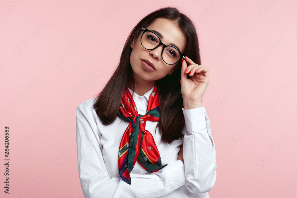 Young confident brunette business female wearing white shirt and scarf, holding her eyeglasses isolated over pink background.