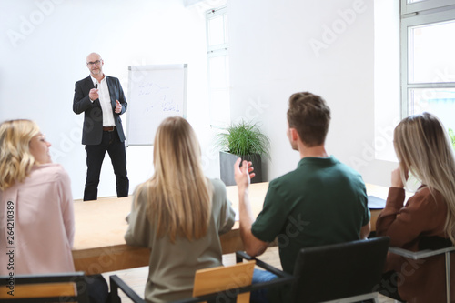 Junge Erwachsene hören einem älteren Vortragenden zu