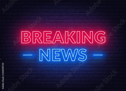 Neon breaking news sign on brick wall background.