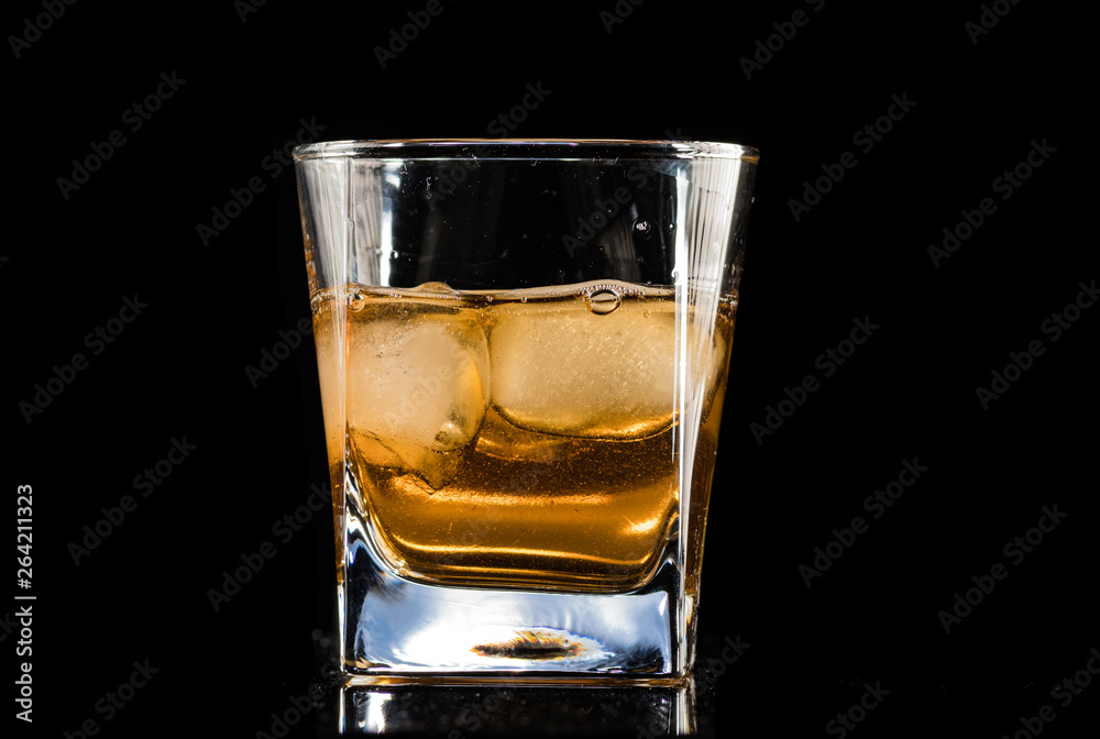 whiskey with ice in a steaming glass on a black background whiskey with ice in a steaming glass on a black background