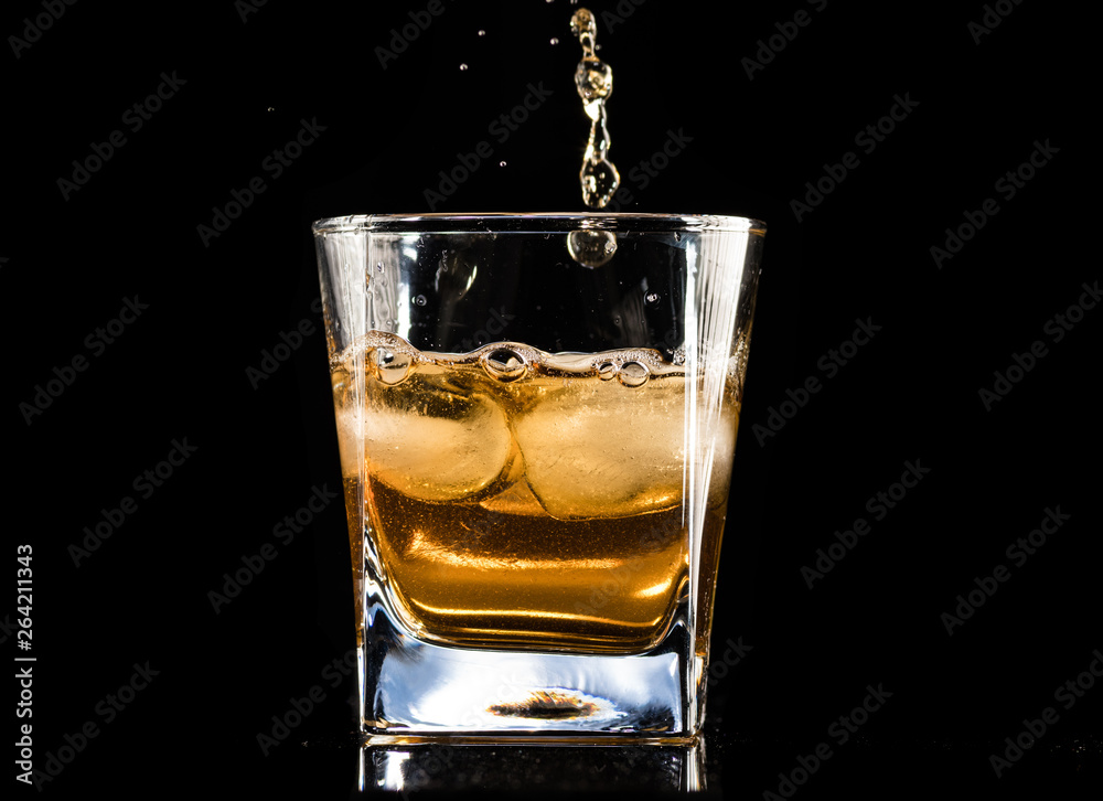 whiskey with ice in a steaming glass on a black background whiskey with ice in a steaming glass on a black background