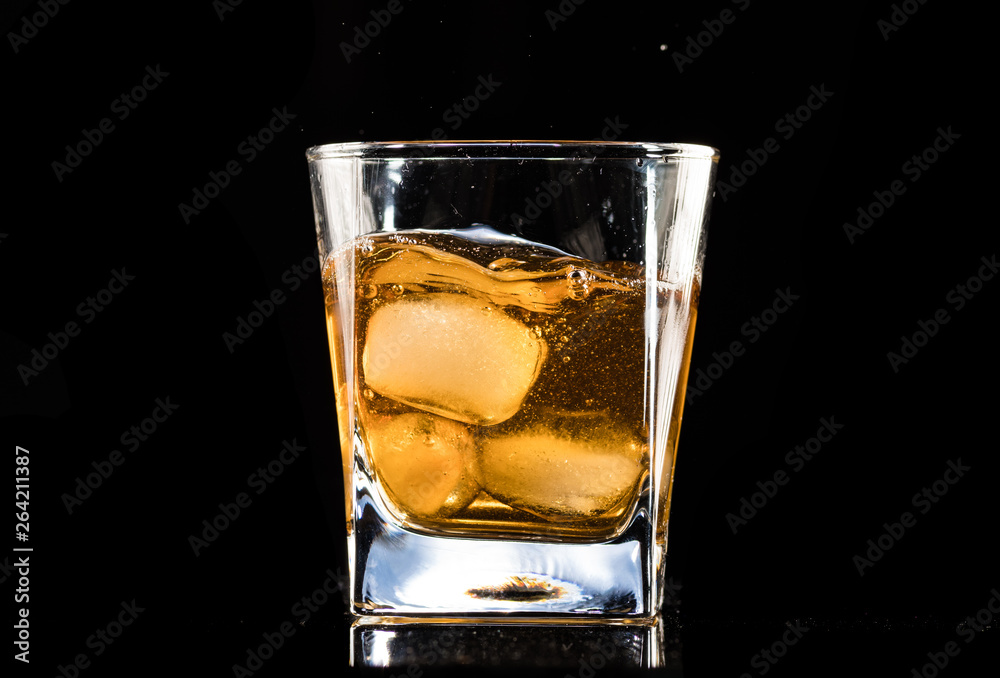 whiskey with ice in a steaming glass on a black background whiskey with ice in a steaming glass on a black background