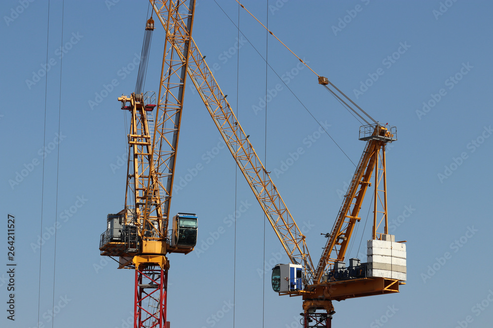 Construction cranes isolated on clear blue sky background. Concept of housing construction or heavy cargo loading work Construction cranes isolated on clear blue sky background. Concept of housing construction or heavy cargo loading work