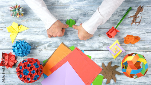 Man hands create beautiful origami toy. Man folding paper frog, top view. Traditional origami paper folding.