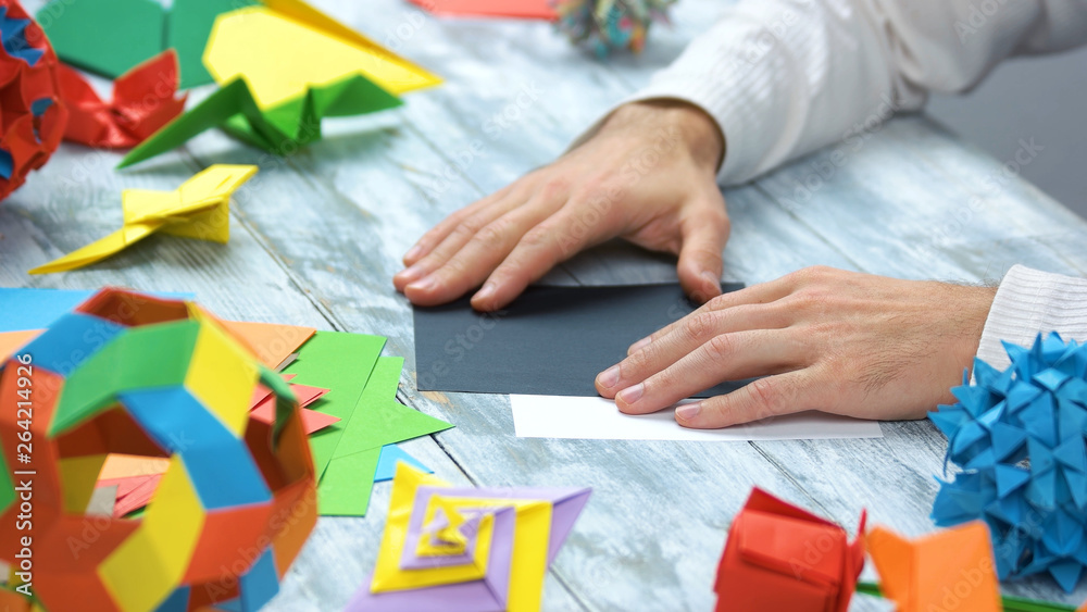 Man doing black origami swan. Lesson of japanese paper folding. How to make paper crane. Man doing black origami swan. Lesson of japanese paper folding. How to make paper crane.