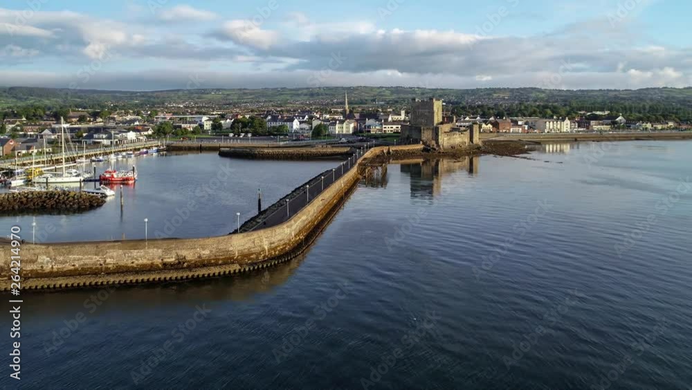 Medieval Norman Castle and harbor in Carrickfergus near Belfast in sunrise light. Aerial 4K flyby video with water reflection harbor/marina, breakwater and town Medieval Norman Castle and harbor in Carrickfergus near Belfast in sunrise light. Aerial 4K flyby video with water reflection harbor/marina, breakwater and town