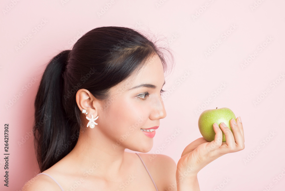 Healthy girl eating green apple on pink background Healthy girl eating green apple on pink background