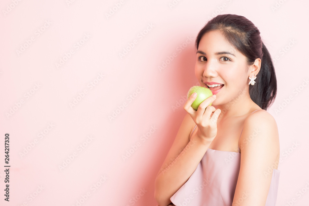 Healthy girl eating green apple on pink background Healthy girl eating green apple on pink background