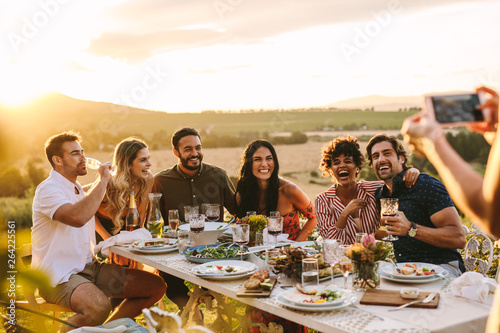 Woman taking picture of her friends at dinner party Fototapeta