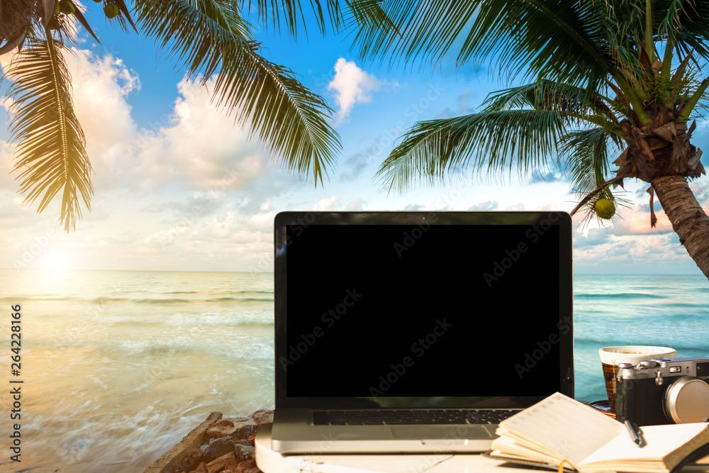Mockup image of laptop with empty screen with camera,notebook,coffee cup on table with at landscape early morning sunrise over the sea,working on the beach,Freelance work and traveler concept. Mockup image of laptop with empty screen with camera,notebook,coffee cup on table with at landscape early morning sunrise over the sea,working on the beach,Freelance work and traveler concept.