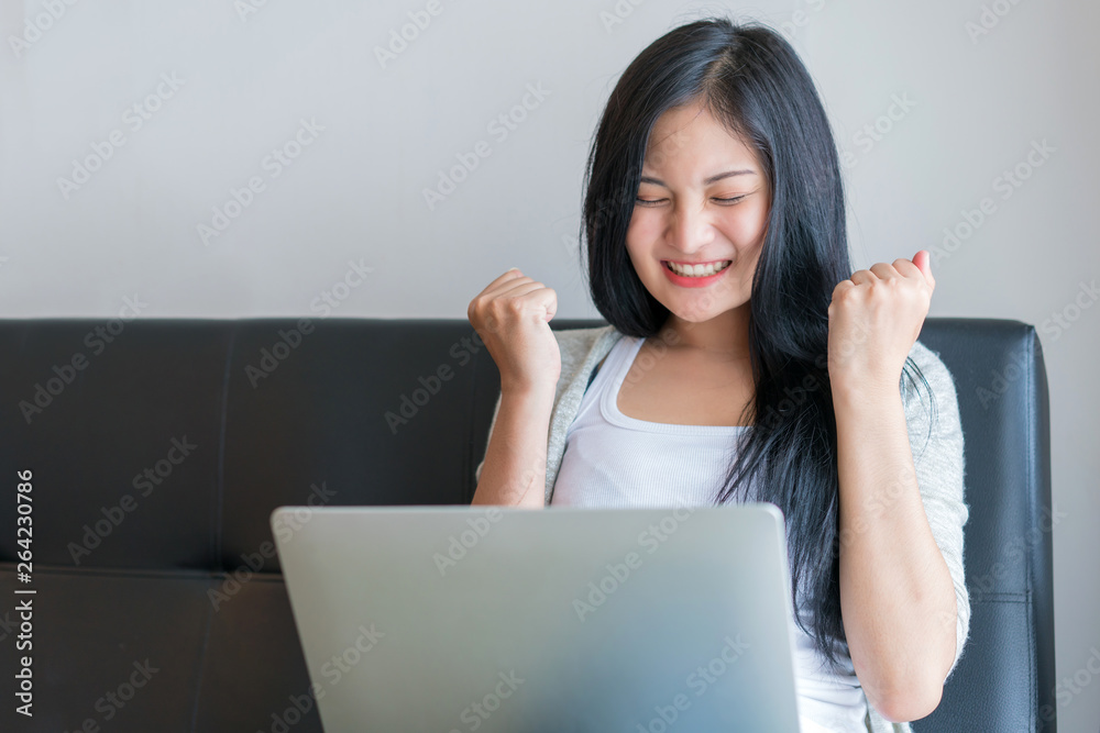Young woman working on a laptop sitting on sofa at home Young woman working on a laptop sitting on sofa at home