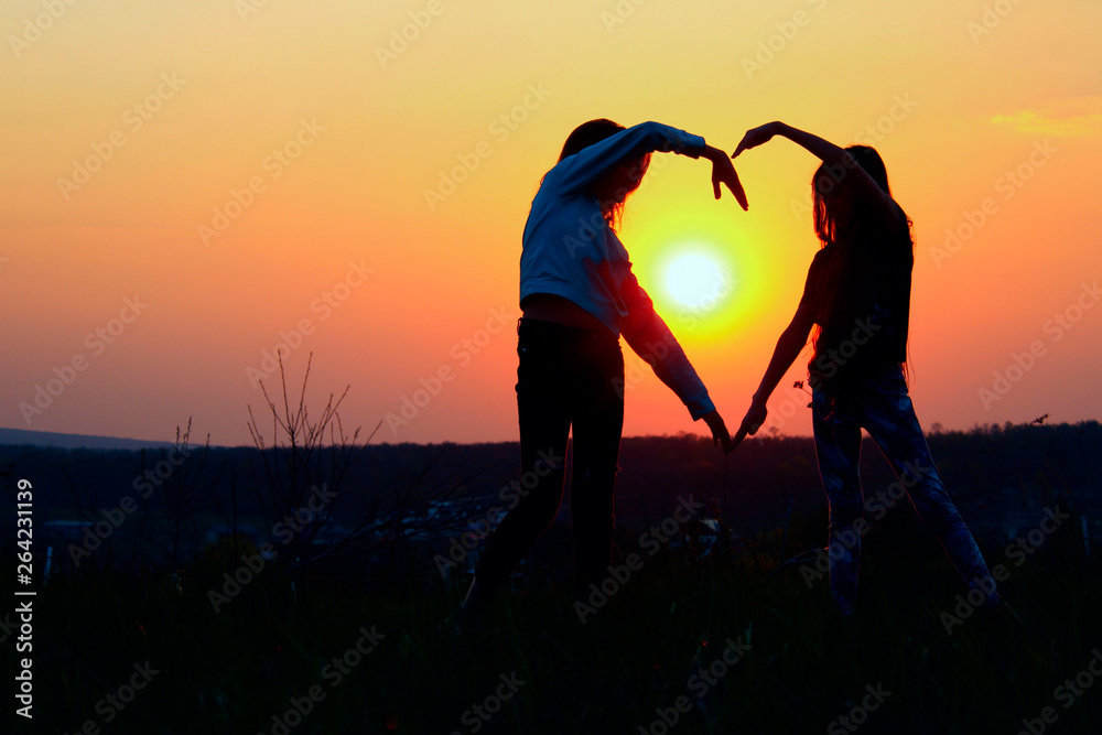 Young Female Couple Making Heart Shape With Hands At Sunset. Abstract