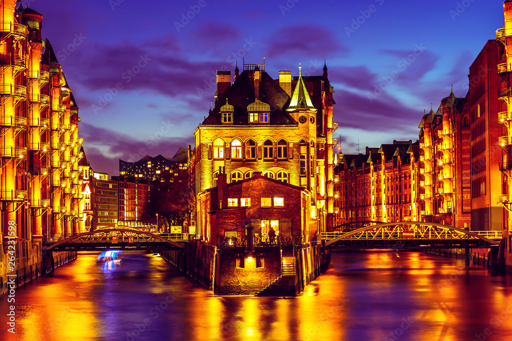Fototapeta premium The Warehouse district Speicherstadt during twilight sunset in Hamburg, Germany. Illuminated warehouses in Hafencity quarter in Hamburg.