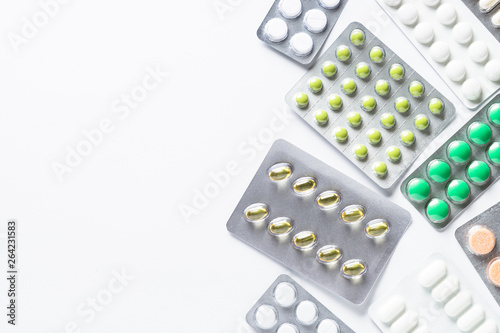 Pills in a blister and vitamins on white background flatlay.