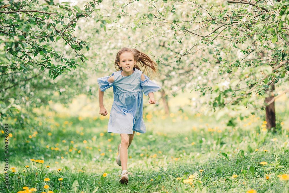 Adorable little girl in blooming apple garden on beautiful spring day Adorable little girl in blooming apple garden on beautiful spring day