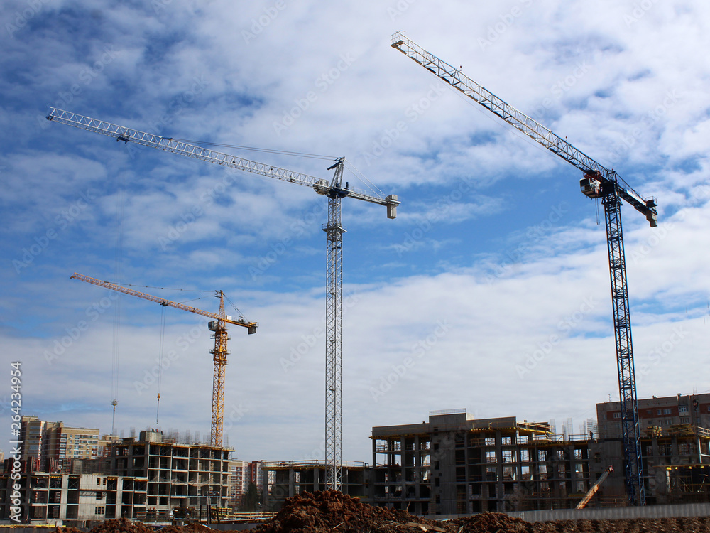 Construction site tower cranes against blue sky Construction site tower cranes against blue sky