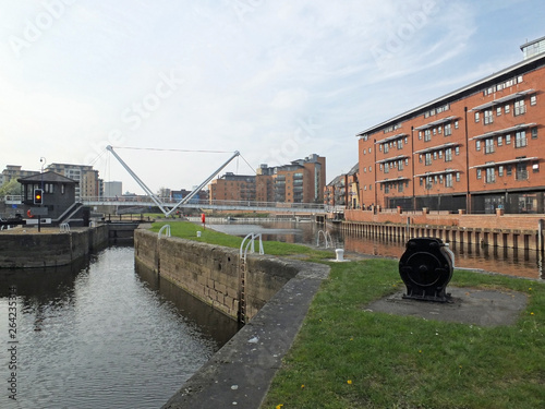 the leeds lock entrance to clarence dock with footbridge over the river aire and historic gates and mooring area surrounded by modern apartment developments