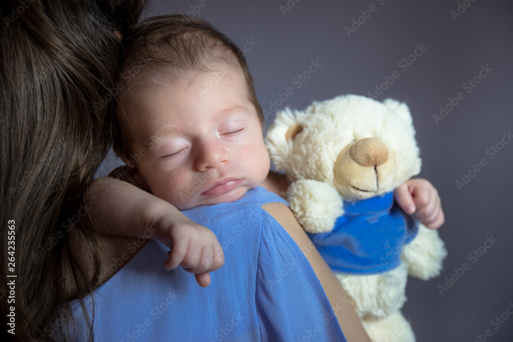 Close-up photo of young mom holding her newborn baby on her shoulder. Close-up photo of young mom holding her newborn baby on her shoulder.