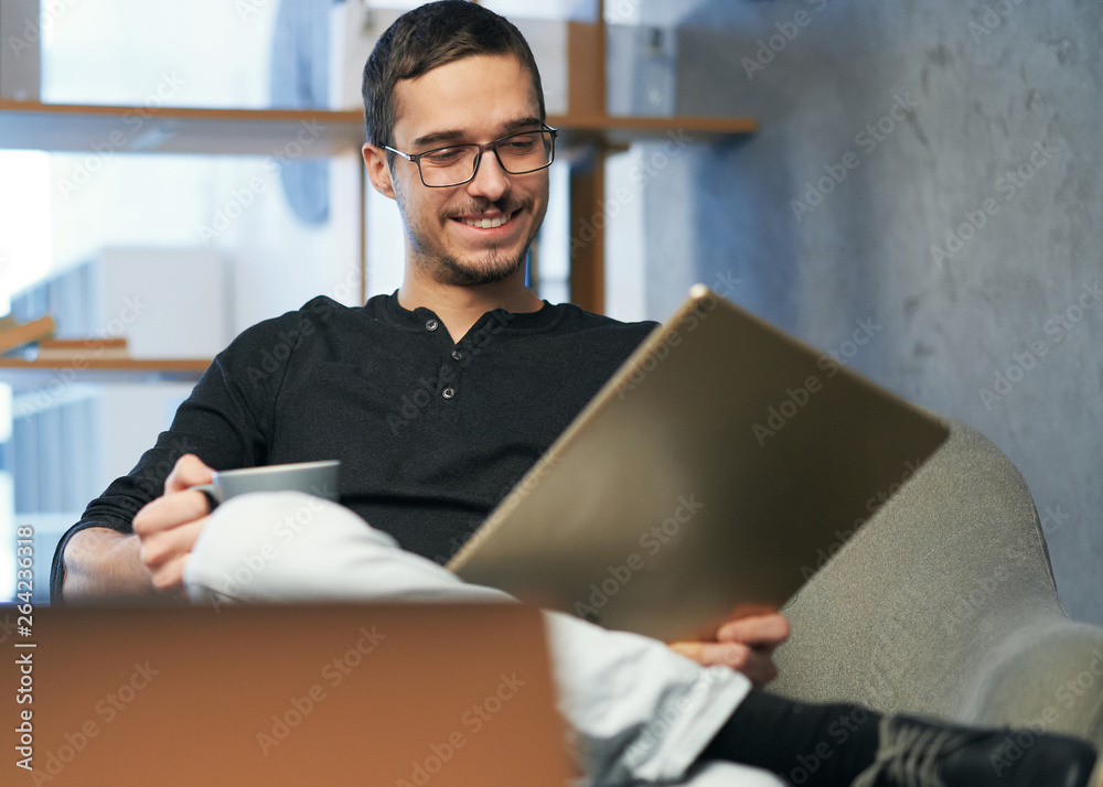 Young man working with computer, phone and tablet at the table while drinking coffee Young man working with computer, phone and tablet at the table while drinking coffee