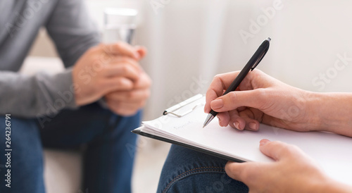 Psychologist taking notes during session with patient photo