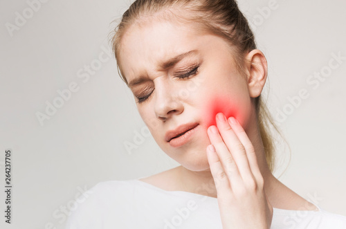 Young woman suffering from toothache, touching her cheek photo
