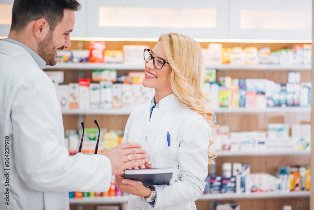 Two cheerful pharmacists talking in hospital pharmacy.
