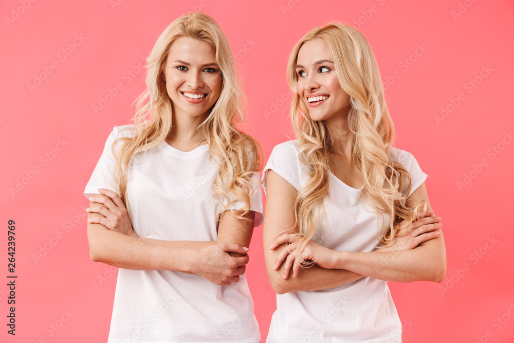 Happy blonde twins wearing in t-shirts posing with crossed arms Happy blonde twins wearing in t-shirts posing with crossed arms