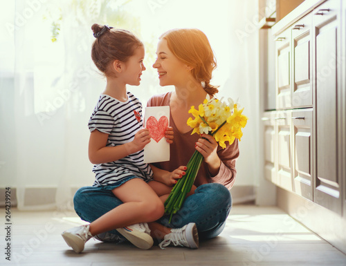 happy mother's day! child daughter   gives mother a bouquet of flowers to narcissus and gift. photo