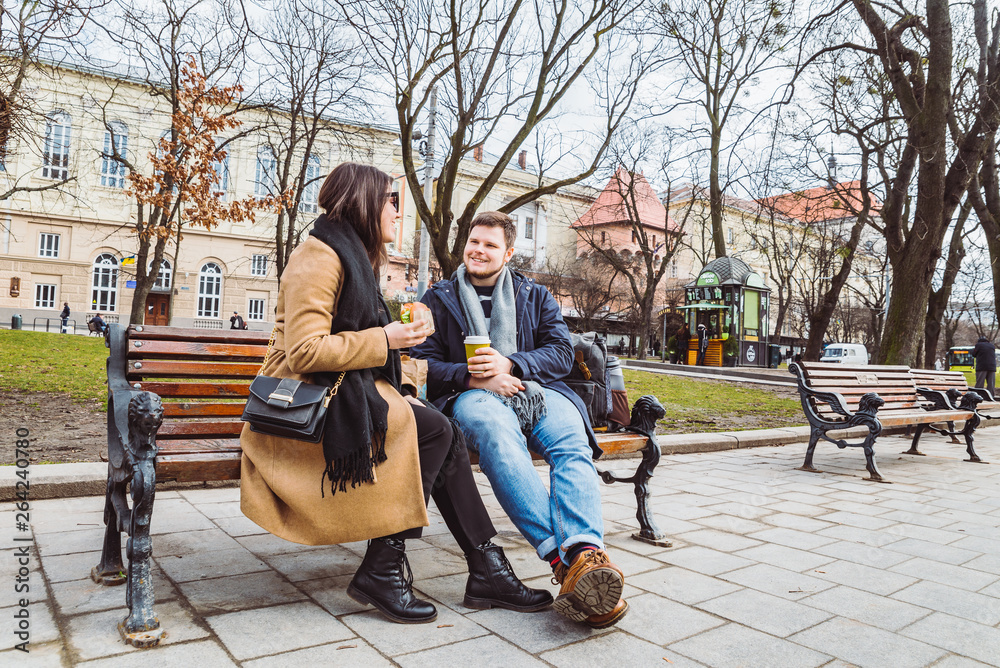 Obraz premium young adult couple eating fast food on bench of city park