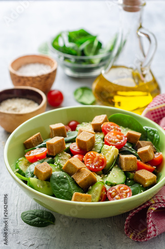 Vegan salad with spinach, cucumber, tomatoes, avocado, fried tofu and sesame. Selective focus.