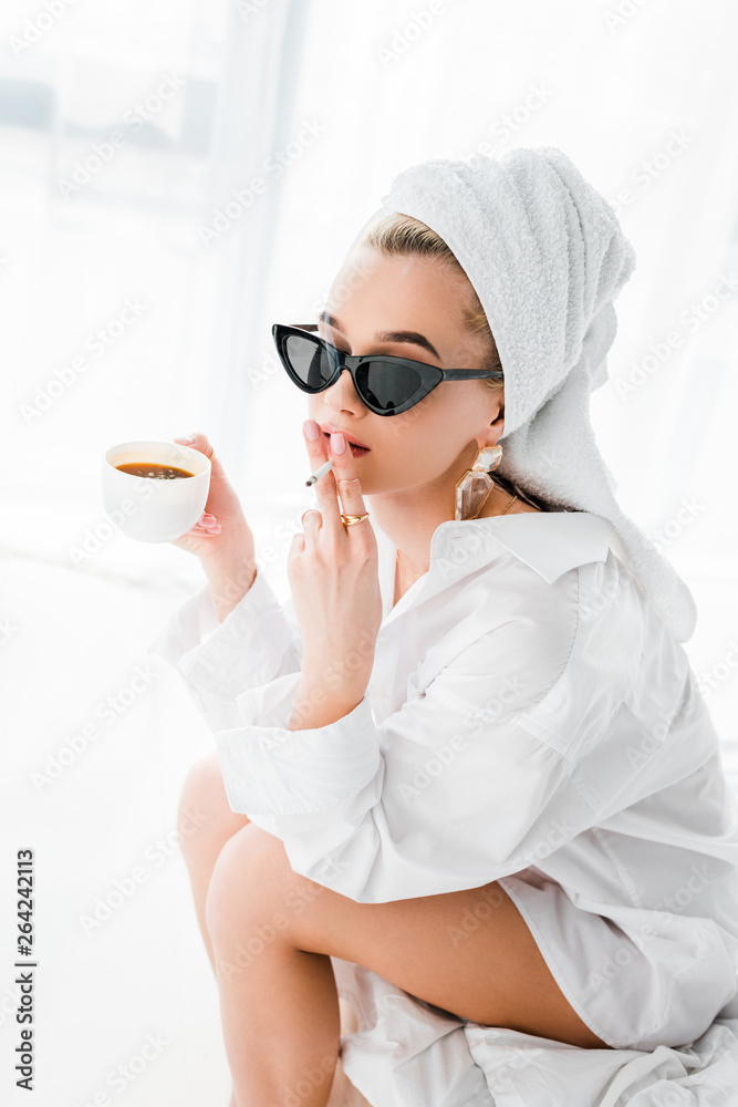 young stylish woman in jewelry and sunglasses with towel on head and cup of coffee smoking cigarette at morning young stylish woman in jewelry and sunglasses with towel on head and cup of coffee smoking cigarette at morning