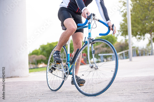 Unrecognizable young male cyclist in sportswear cycling bike on road in park © pablobenii