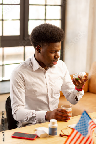 Nice handsome man looking at the bottle with pills