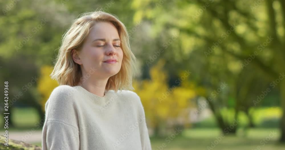 Pretty female taking a deep breath in front of colorful park scenery Pretty female taking a deep breath in front of colorful park scenery