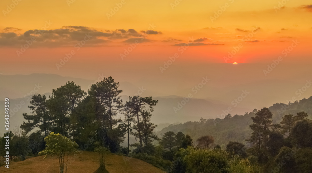 Mountain view evening of Top hill around with soft fog with yellow and red sun light in the sky background, sunset at Huai Nam Dang National Park, Chiang Mai, Thailand.